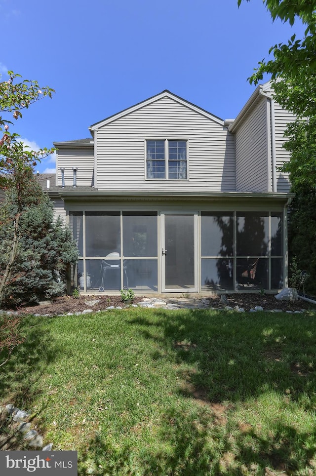 rear view of property featuring a sunroom and a yard
