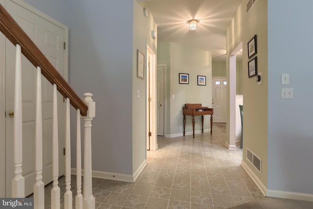corridor featuring stairway, baseboards, and tile patterned flooring