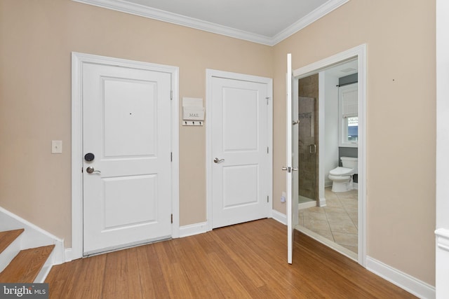 unfurnished bedroom featuring ornamental molding, light wood-style flooring, baseboards, and ensuite bathroom