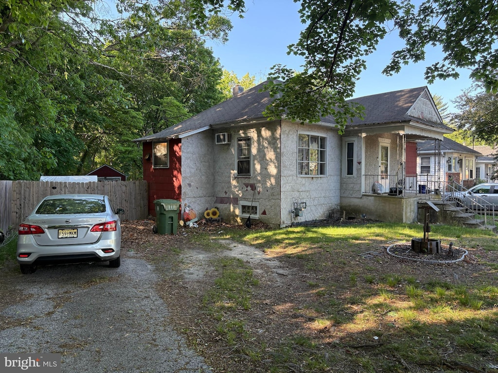 view of home's exterior featuring covered porch, fence, and a shingled roof