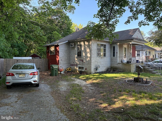 view of home's exterior featuring covered porch, fence, and a shingled roof