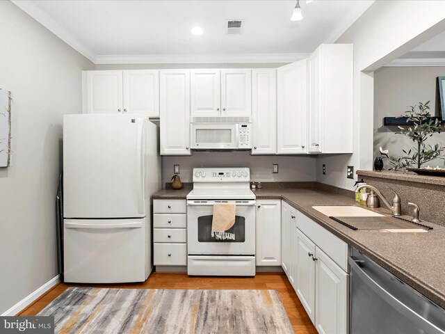 kitchen featuring white appliances, a sink, white cabinets, ornamental molding, and light wood finished floors