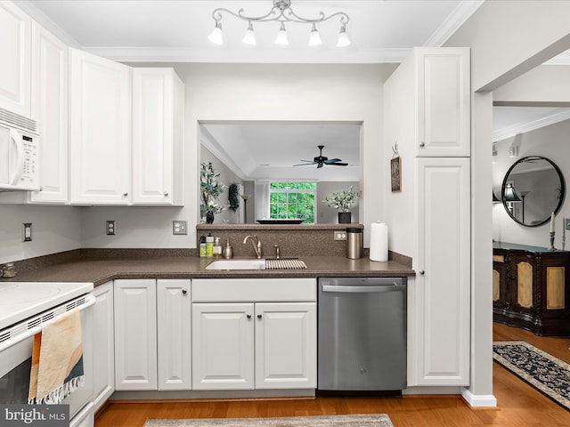 kitchen featuring white appliances, a sink, crown molding, dark countertops, and light wood-type flooring