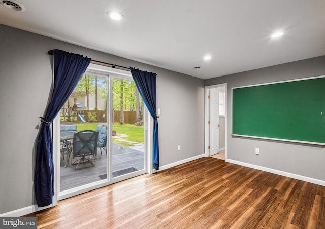 unfurnished room with wood finished floors, recessed lighting, and baseboards