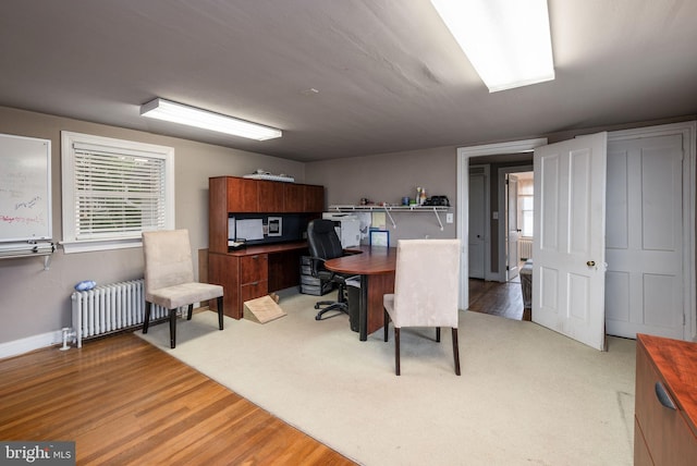 office space with baseboards, radiator heating unit, plenty of natural light, and wood finished floors
