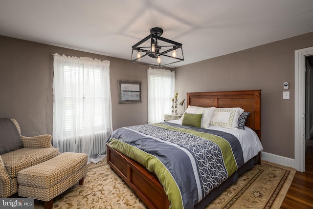 bedroom featuring wood finished floors, baseboards, and a notable chandelier
