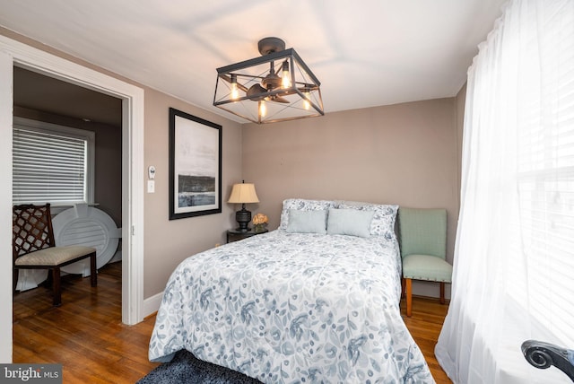 bedroom with a chandelier, baseboards, and wood finished floors