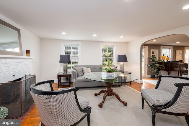 living room with wood finished floors, a fireplace, arched walkways, and recessed lighting