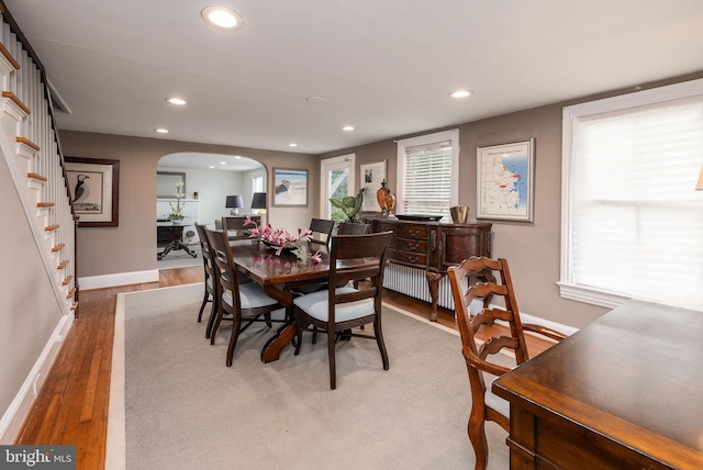 dining area featuring recessed lighting, baseboards, wood finished floors, arched walkways, and stairway