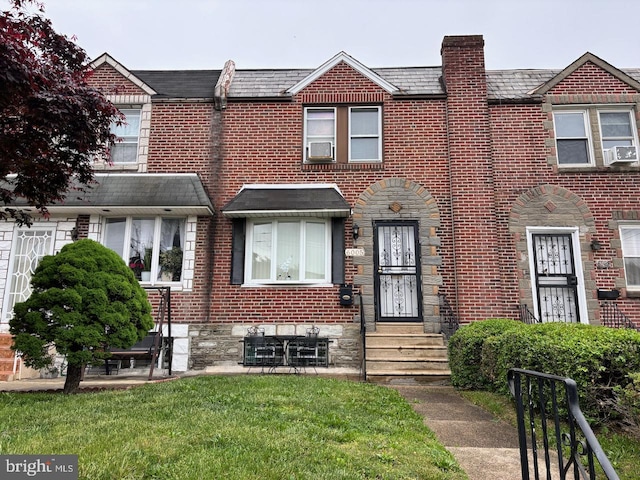 view of property with brick siding, a high end roof, and a front lawn