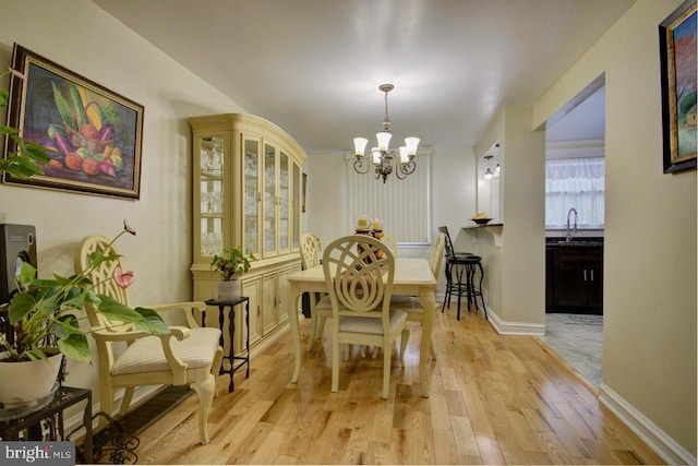 dining space featuring a chandelier, light wood finished floors, and baseboards