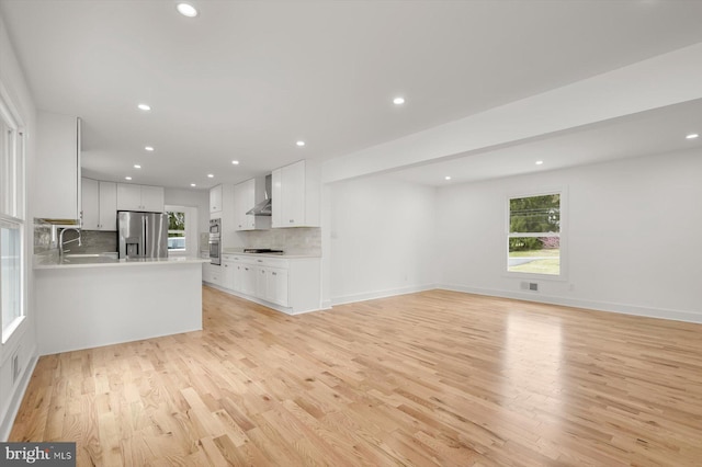 9828 Watts Branch Dr, Rockville, MD 20850 - unfurnished living room with light wood-style flooring, recessed lighting, healthy amount of natural light, and a sink
