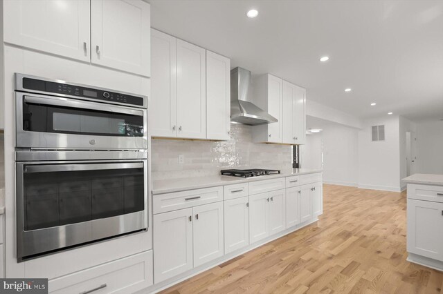 9828 Watts Branch Dr, Rockville, MD 20850 - kitchen with double oven, wall chimney range hood, light countertops, white cabinets, and recessed lighting