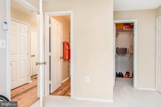 unfurnished bedroom featuring a walk in closet, a closet, baseboards, and carpet flooring