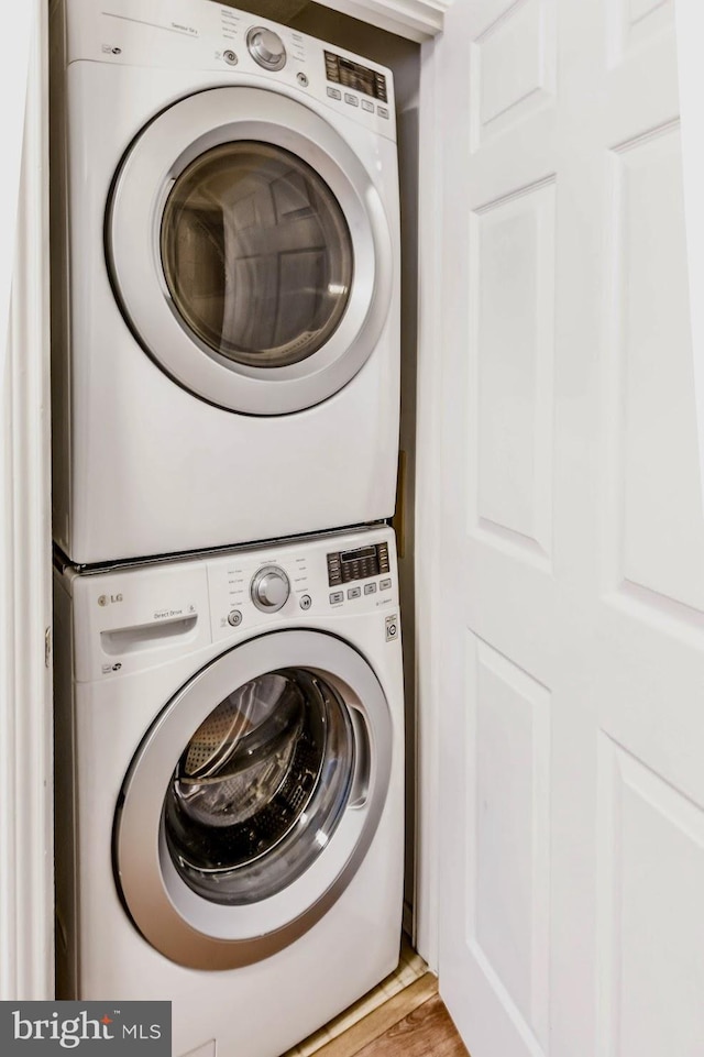 laundry room featuring stacked washer / drying machine and light wood-type flooring