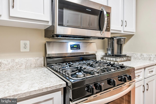 kitchen featuring stainless steel appliances, white cabinetry, and light countertops