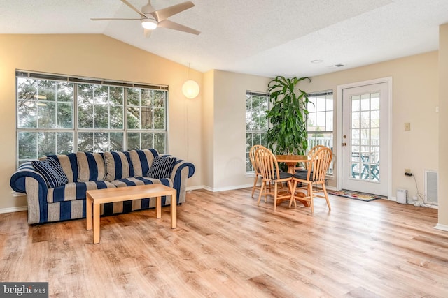 living area featuring plenty of natural light, a ceiling fan, wood finished floors, lofted ceiling, and a textured ceiling