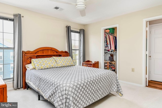 bedroom with a closet, a walk in closet, baseboards, and light colored carpet