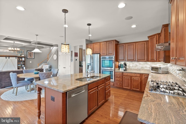 13859 Barrymore Ct, Gainesville, VA 20155 - kitchen featuring stainless steel appliances, a sink, light wood-style floors, light stone counters, and a center island with sink