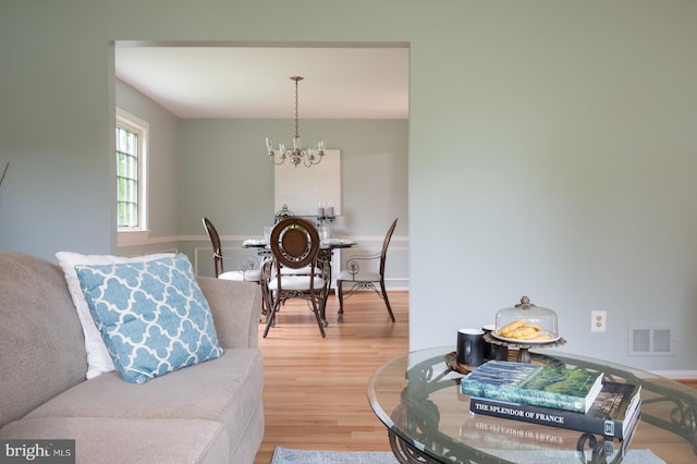 living room featuring an inviting chandelier, visible vents, and wood finished floors