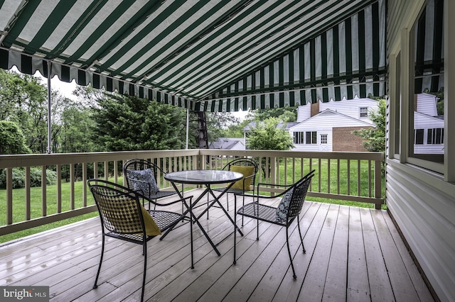 wooden terrace with outdoor dining area and a lawn