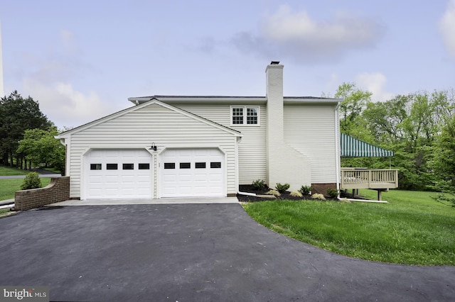 view of home's exterior with a lawn, driveway, a chimney, and a garage