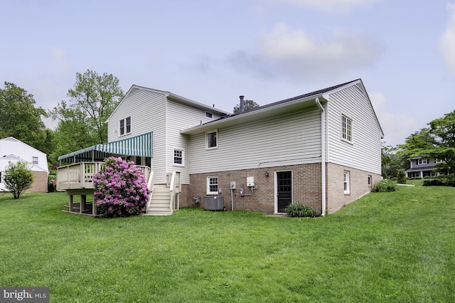 back of house featuring a lawn, cooling unit, brick siding, and a deck
