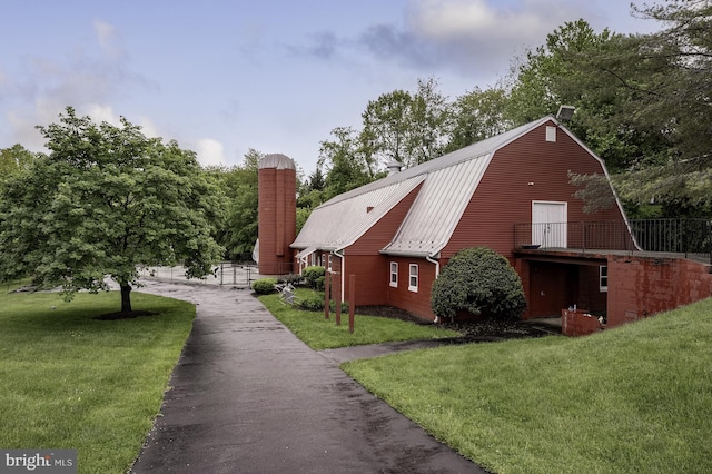 view of side of home featuring a chimney, a yard, a gambrel roof, and metal roof