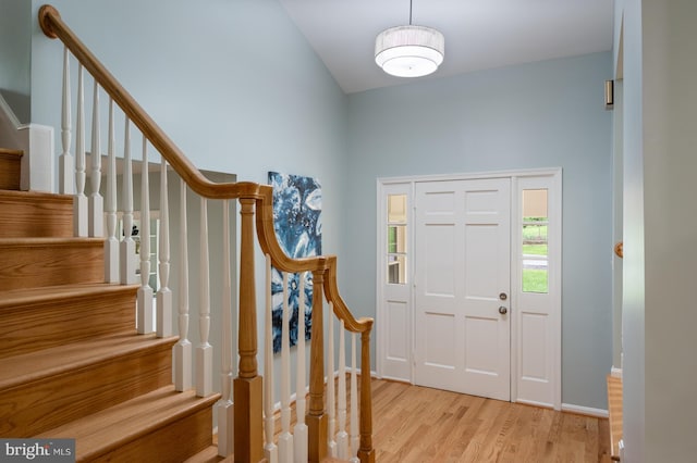 foyer entrance featuring baseboards, stairs, and light wood-style flooring