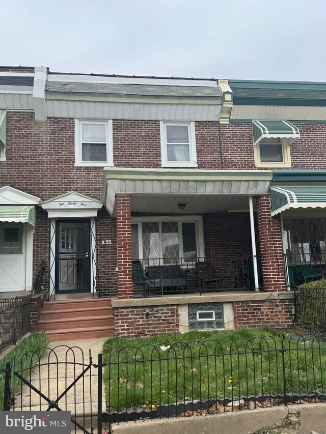 235 E Price St, Philadelphia, PA 19144 - townhome / multi-family property featuring a porch, entry steps, brick siding, and a fenced front yard