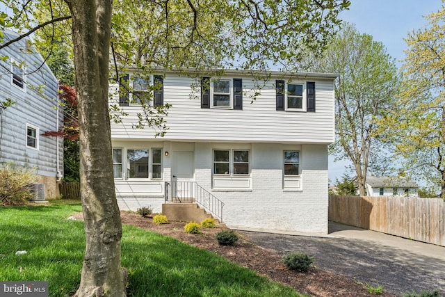 colonial house with brick siding, fence, and central air condition unit
