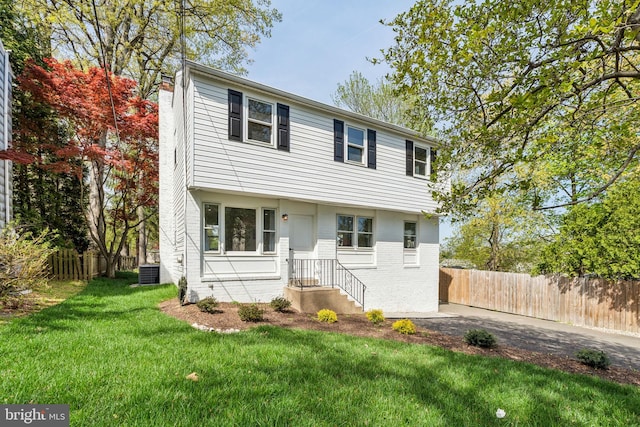colonial inspired home with a chimney, brick siding, and central air condition unit