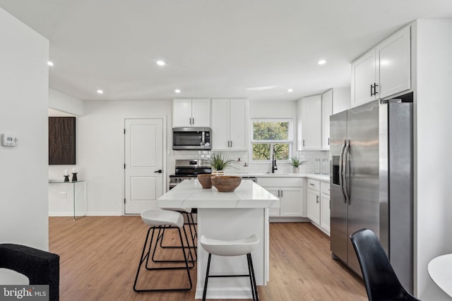 kitchen with stainless steel appliances, a sink, light wood-style floors, tasteful backsplash, and recessed lighting