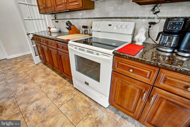 kitchen featuring electric range, brown cabinetry, tasteful backsplash, and dark stone countertops