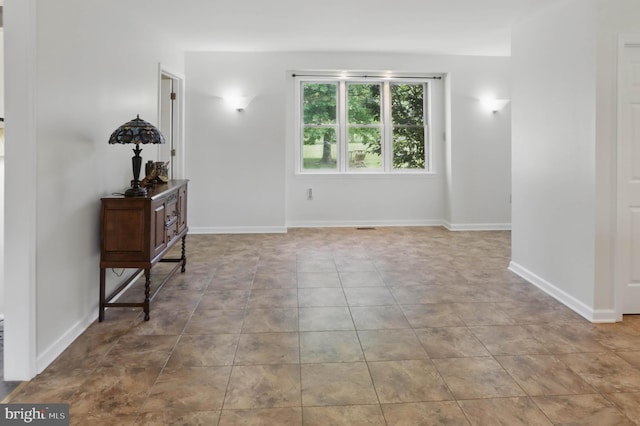 tiled empty room featuring baseboards