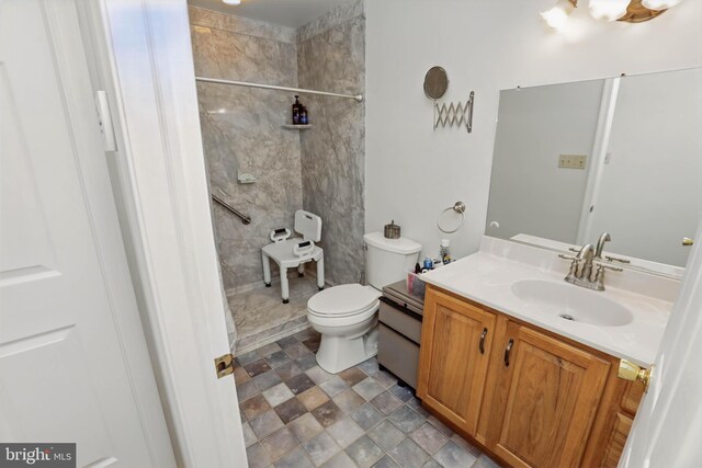 full bathroom with vanity, toilet, tiled shower, and stone finish flooring