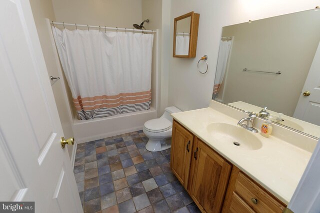 full bath featuring stone finish floors, vanity, toilet, and shower / bath combination with curtain