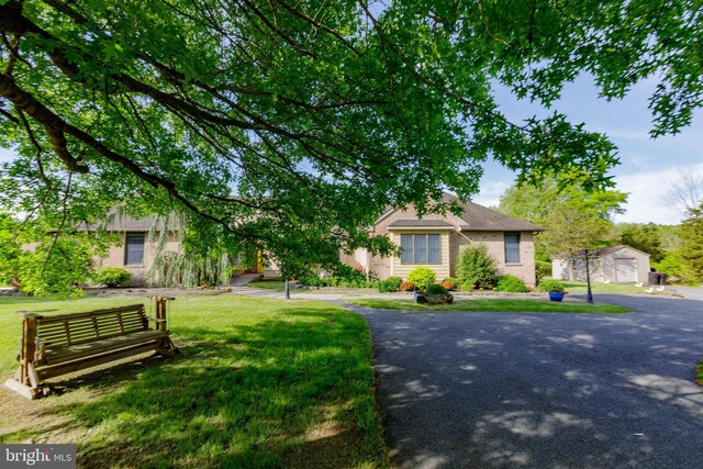 obstructed view of property featuring brick siding and a front yard