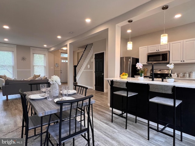 dining room featuring stairway, light wood-type flooring, and recessed lighting