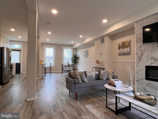 living area featuring recessed lighting, a wealth of natural light, visible vents, and wood finished floors