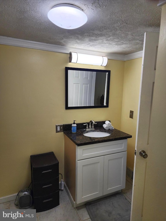 bathroom featuring a textured ceiling, baseboards, vanity, and ornamental molding