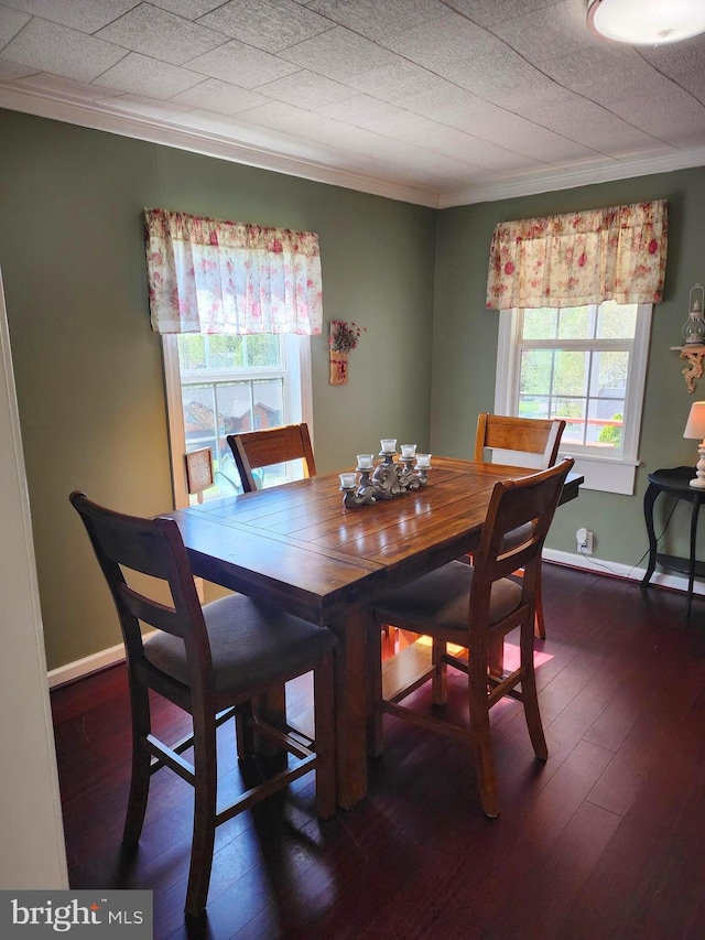 dining space with crown molding, baseboards, and hardwood / wood-style flooring