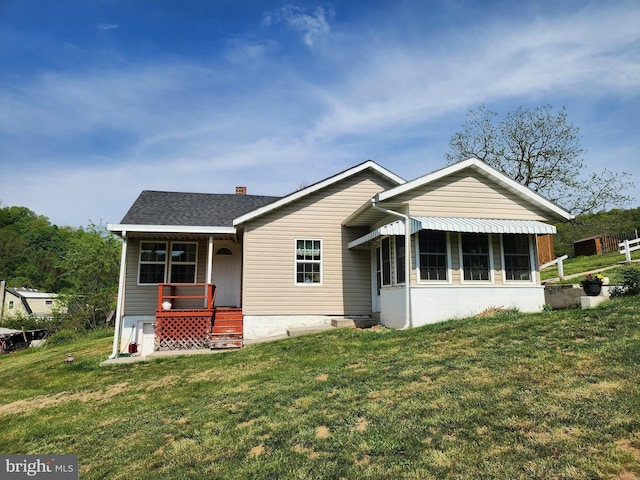 view of front of house with a chimney, a front yard, and covered porch