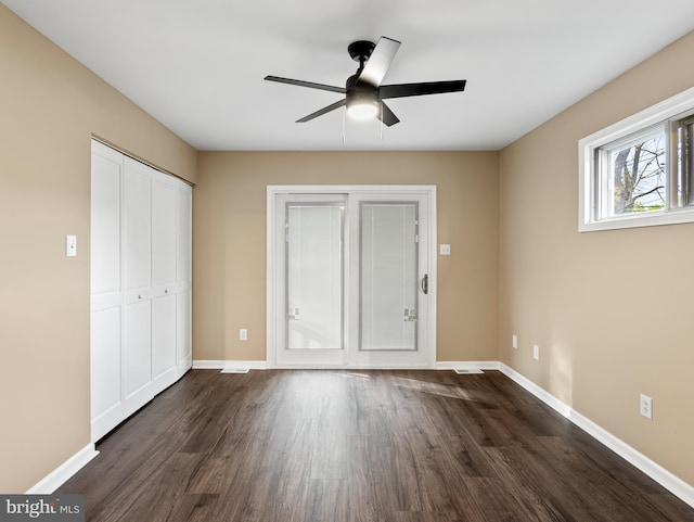 unfurnished bedroom with dark wood-style flooring, baseboards, a closet, and a ceiling fan
