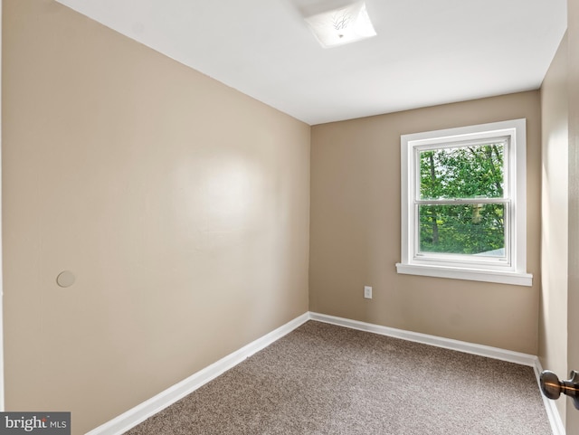 carpeted spare room featuring baseboards