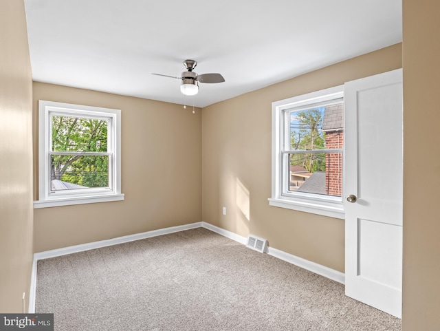 empty room featuring carpet, visible vents, a ceiling fan, and a healthy amount of sunlight