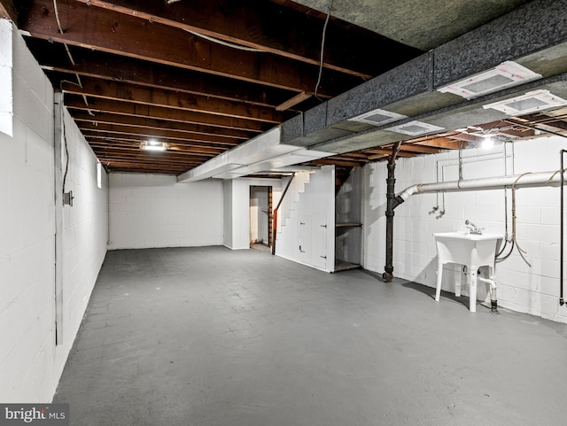 basement featuring a sink, stairway, and concrete block wall