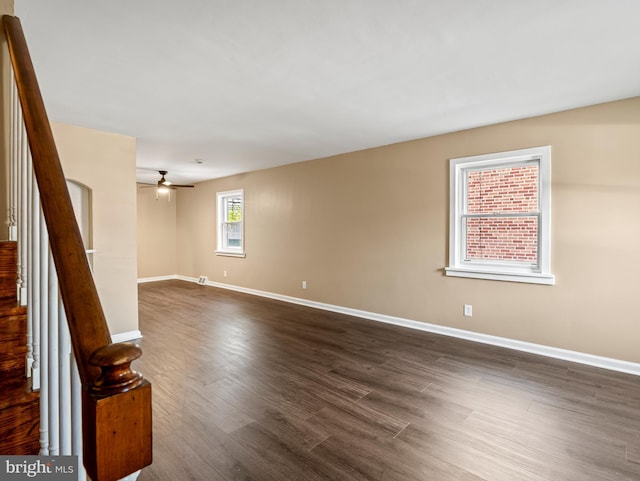 unfurnished room featuring baseboards, stairway, a ceiling fan, and dark wood-style floors