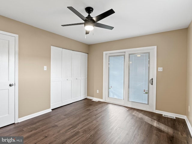 unfurnished bedroom featuring access to exterior, visible vents, dark wood-style flooring, and baseboards
