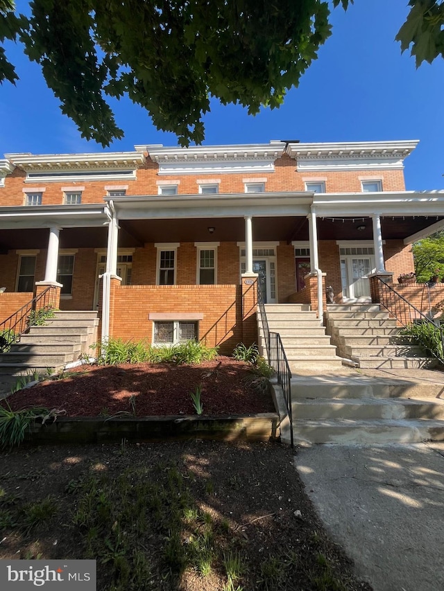 view of property with stairway, a porch, and brick siding
